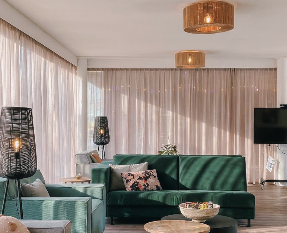 Zorginterieur met groene bank en comfortabele zitplekken voor ontmoeting en rust.